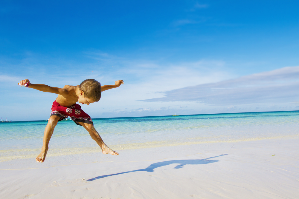 gutt som koser seg på en vakker strand